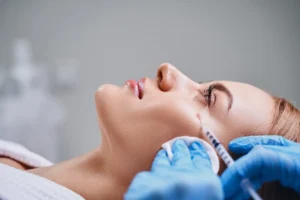 uma jovem esta visitando um cosmetologista e recebendo injecoes de beleza para rejuvenescer o rosto e levantar a pele